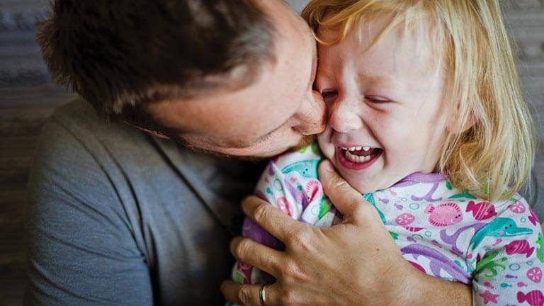 father kissing child on check