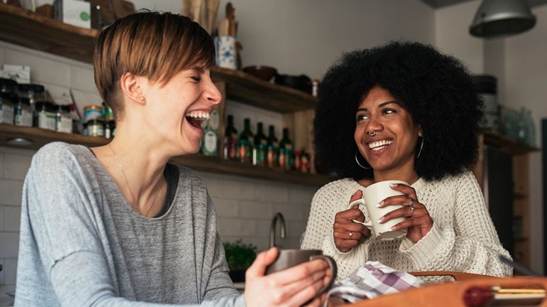 two girls sharing laughing in cafe
