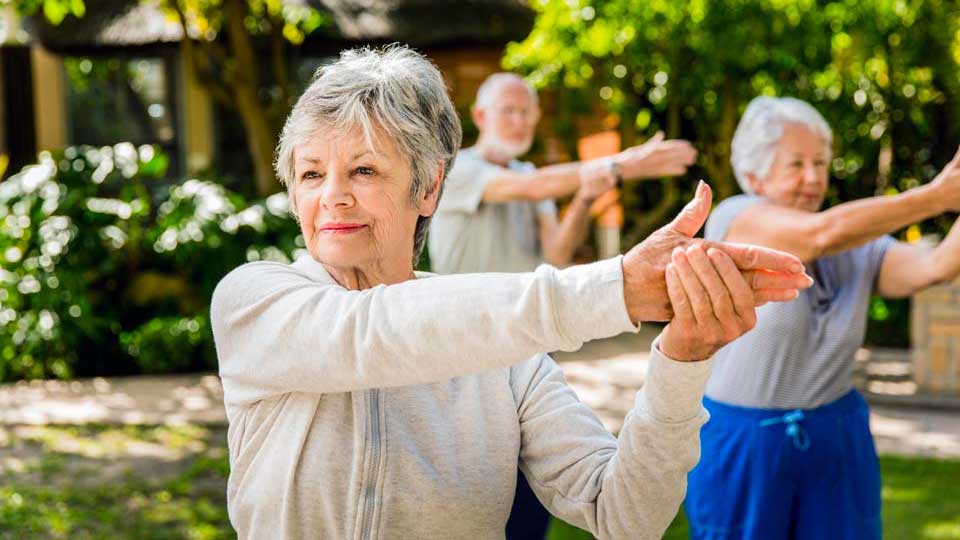 senior woman with friends exercising in yard