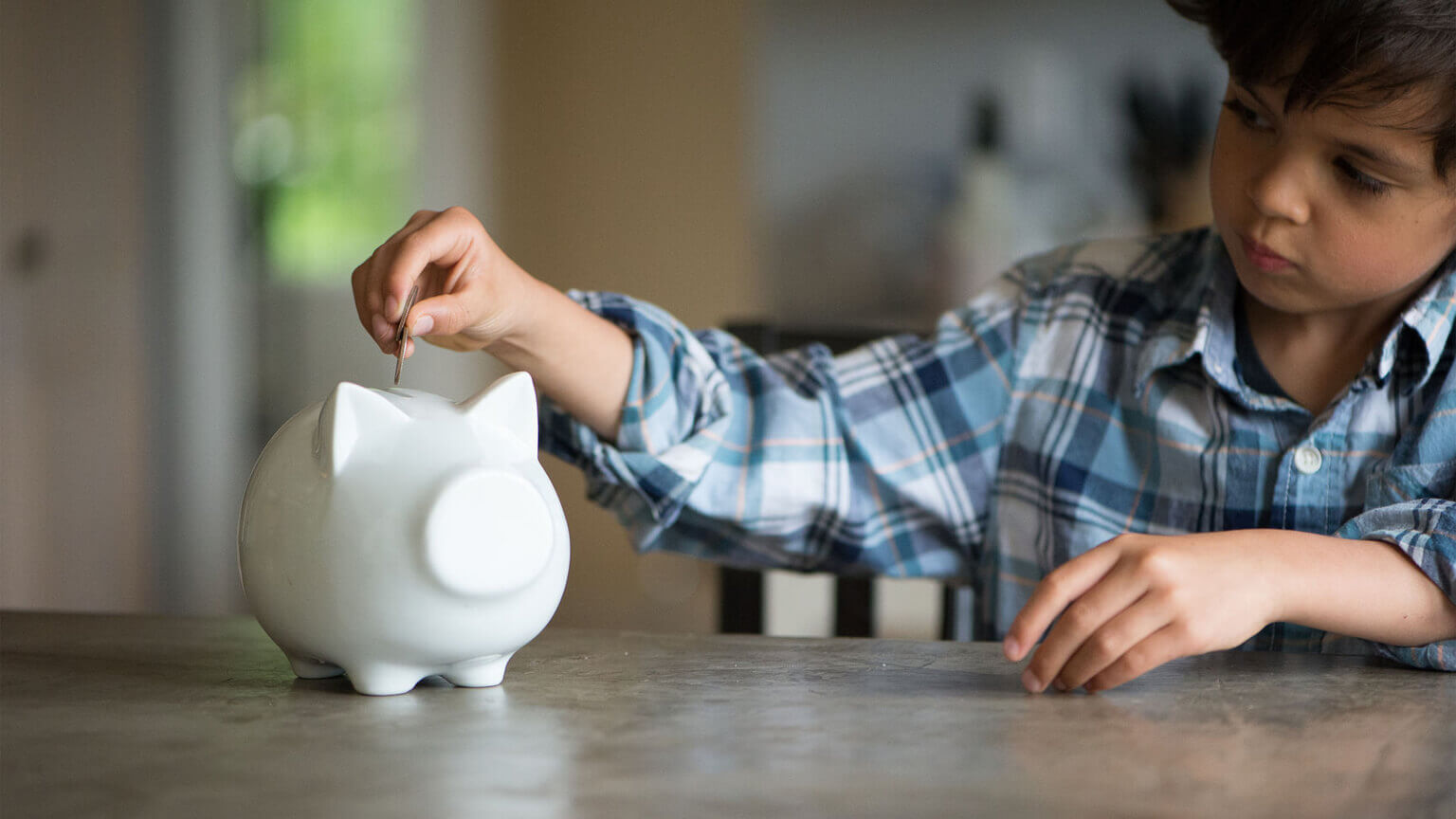 boy putting money in piggy bank