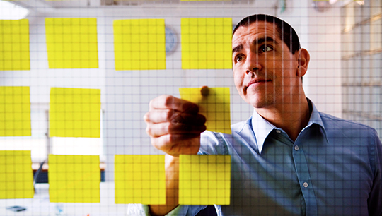 Man organising notes on a work board