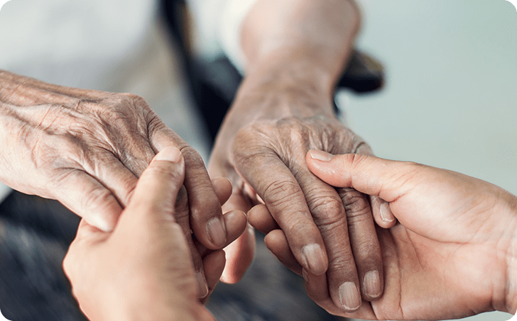 Hands of younger person holding both hands of older person