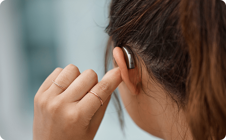 Woman inserting hearing aid