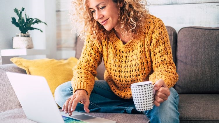 Person using laptop while holding cup