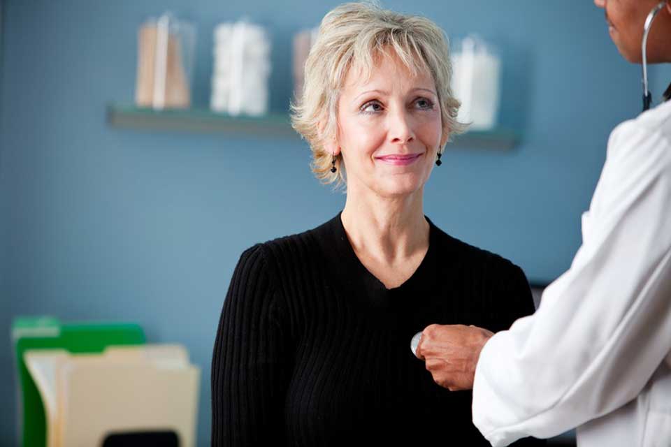 Doctor listening to lady's heart