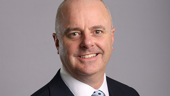 A person in a suit smiling, professional headshot.
