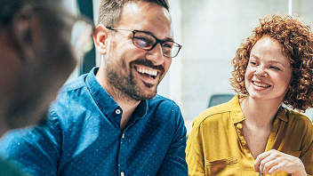 Two people laughing together in a workplace setting.