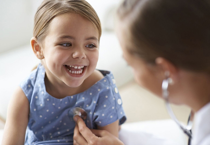 smiling young girl being examined by doctor