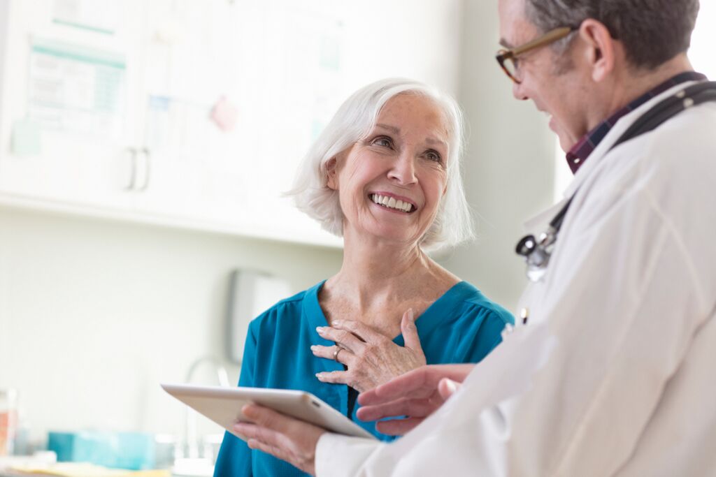 Mature woman smiling, looking at general practitioner