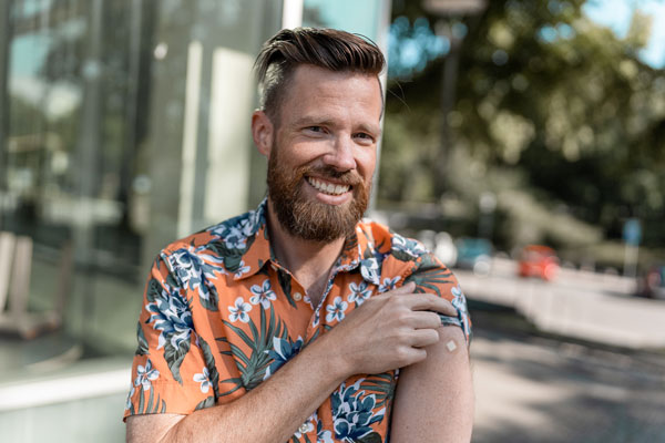 Man in Hawaiian shirt with sticking plaster covering a vaccination site