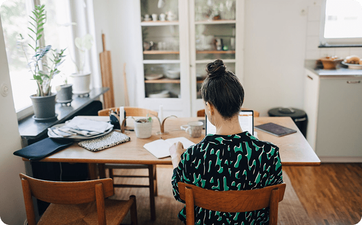 Woman using laptop at kitchen table