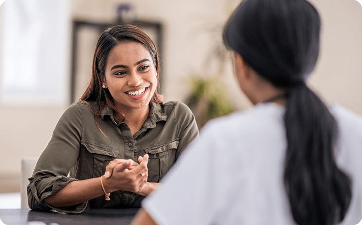 Female patient smiling and talking with medical professional
