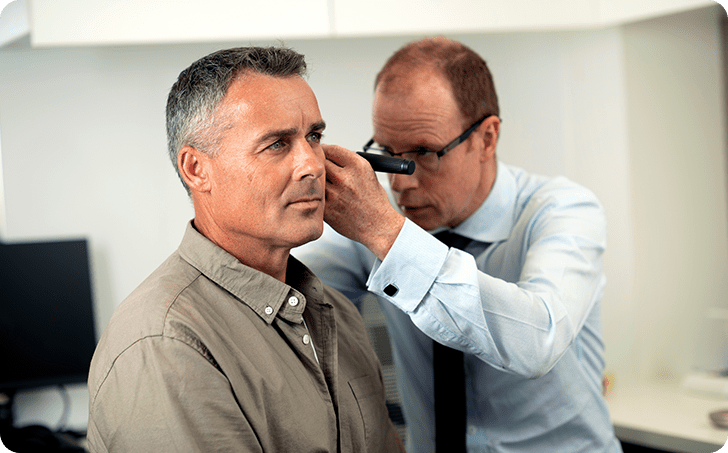 Audiologist examining ear of male patient