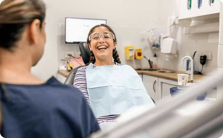 Dentist interacting with smiling child in dentists chair